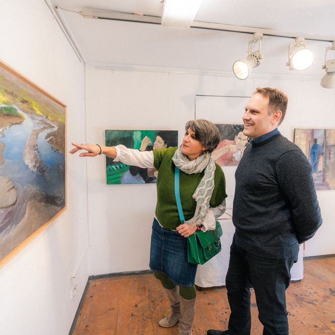 Pärchen betrachten Bilder in einer Galerie.