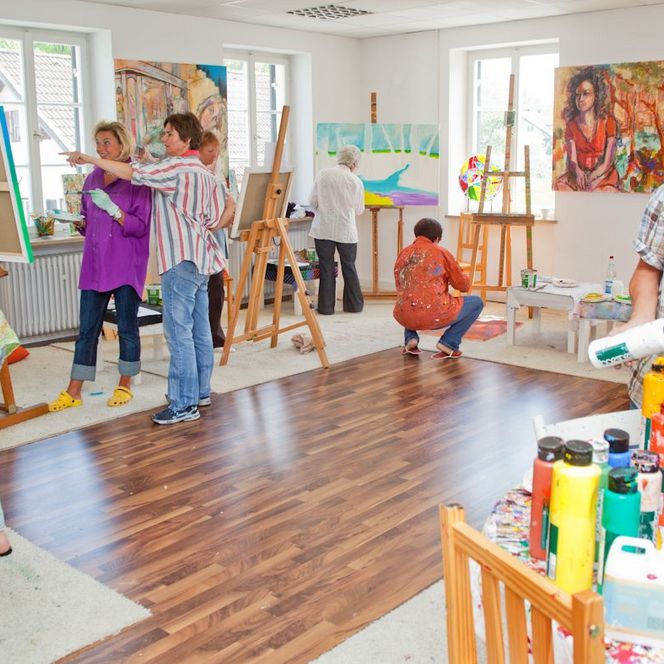 Mehrere Personen malen in einem Atelier.