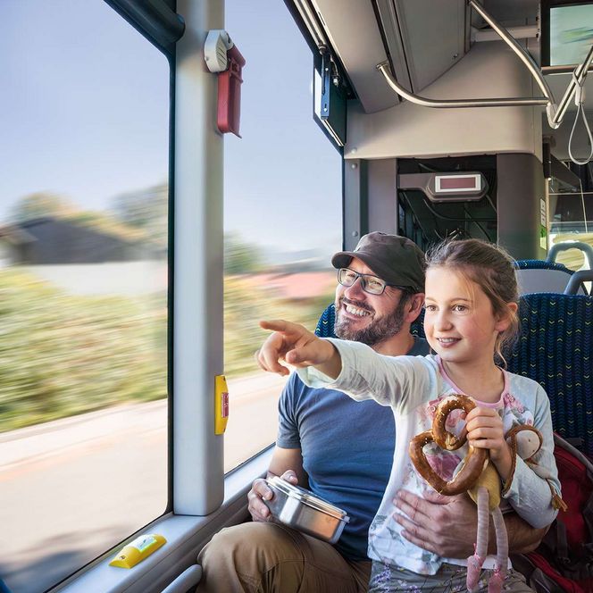 Vater mit Kind im Bus sitzend und aus dem Fenster schauend