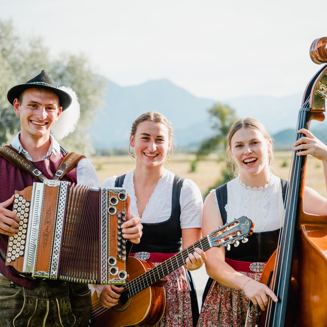 Drei Musiker spielen bei strahlendem Sonnenschein im Murnauer Moos