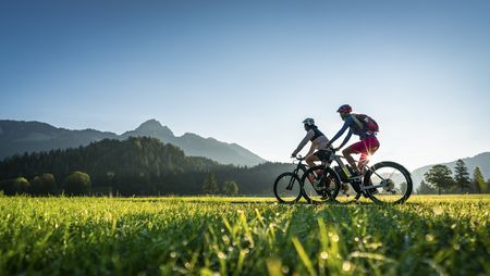 Zwei Radler unterwegs auf dem Bodensee-Königssee-Radweg bei strahlendem Sonnenschein und blauem Himmel.