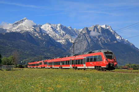 Werdenfelsbahn im Vordergrund eine Blumenwiese mit der Alpspitze und Zugspitze im Hintergrund