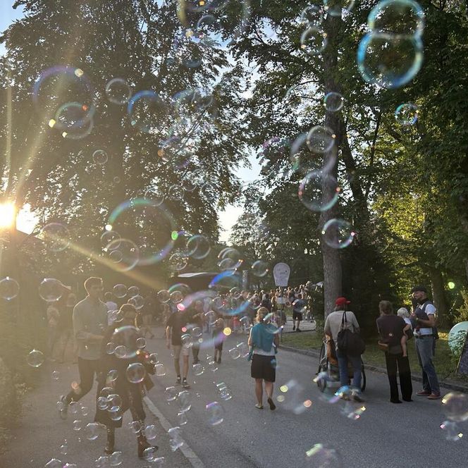 Straßenzug mit Menschen in Abendstimmung mit Seifenblasen im Vordergrund
