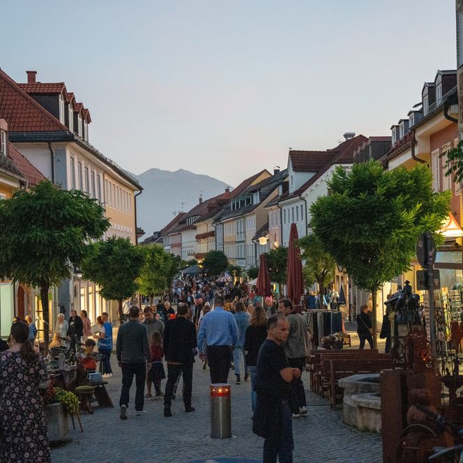 Abendstimmung in der Fußgängerzone Markt Murnau mit Blick Richtung, im Vordergrund einige MenschenSüden 