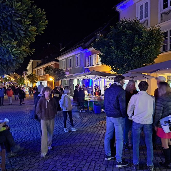 Fußgängerzone Markt Murnau bei Nacht, im Vordergrund einige Menschen
