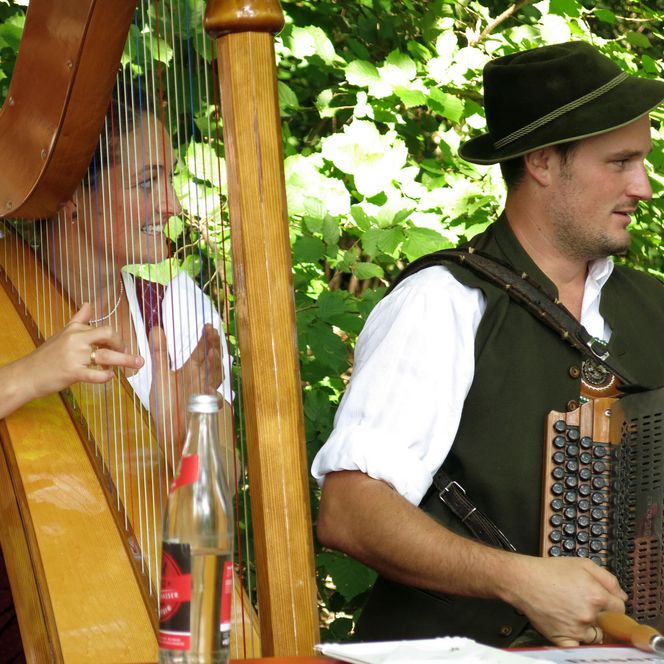 Zwei Musikanten mit Harfe und Ziehharmonika.