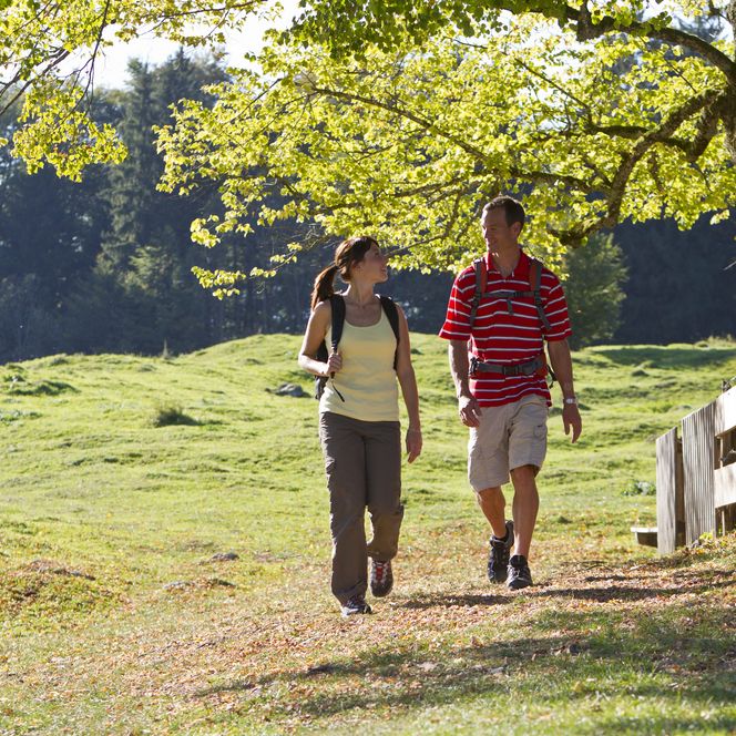 Ein Paar wandert auf einem Wanderweg über eine Wiese.