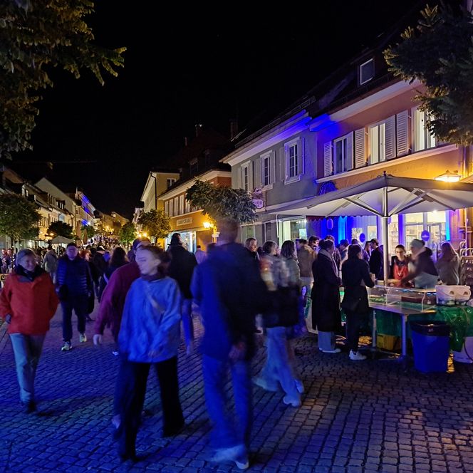 Fußgängerzone bei Dunkelheit, im Vordergrund einige Menschen