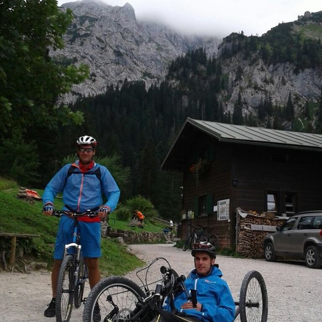 Ein Mann auf einem Fahrrad fährt neben einem Handbike-Fahrer.