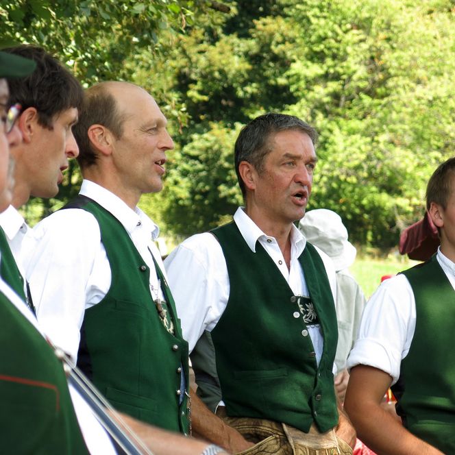 Männer in Tracht singen im Freien.